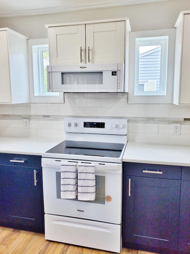121 S Marshall St, New Buffalo, MI 49117 - kitchen featuring white appliances, blue cabinets, decorative backsplash, and light countertops