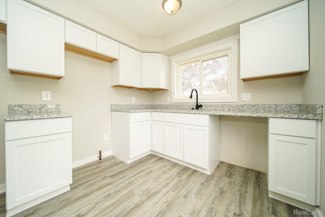 16282 Evergreen Ave, Eastpointe, MI 48021 - kitchen with light wood-type flooring, light stone countertops, white cabinetry, and a sink