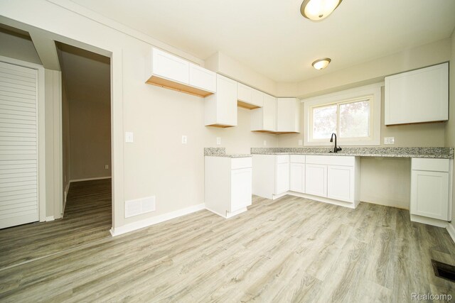 16282 Evergreen Ave, Eastpointe, MI 48021 - kitchen with light wood-style floors, white cabinetry, light stone countertops, baseboards, and a sink