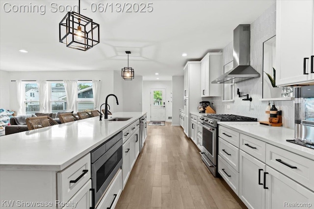 3278 Tyler Ave, Berkley, MI 48072 - kitchen featuring wall chimney exhaust hood, appliances with stainless steel finishes, white cabinets, light countertops, and an island with sink