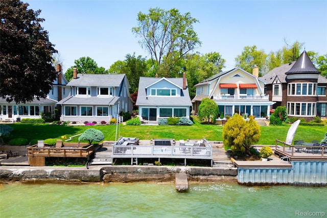29899 E River Rd, Grosse Ile, MI 48138 - rear view of house with a chimney, a lawn, and a deck with water view