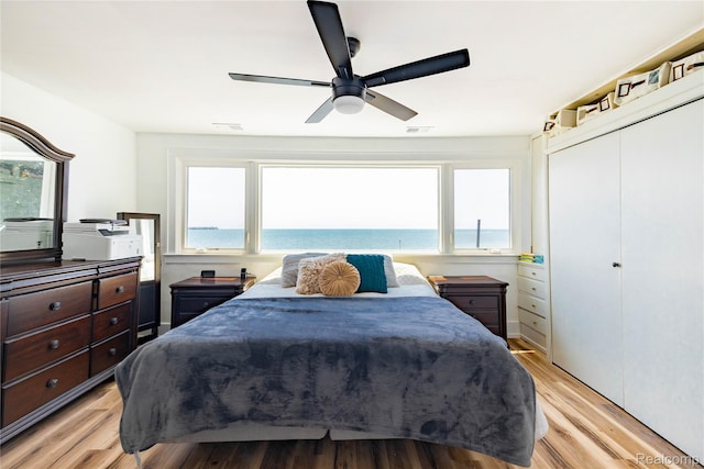29899 E River Rd, Grosse Ile, MI 48138 - bedroom featuring light wood-style floors, ceiling fan, a closet, and a water view