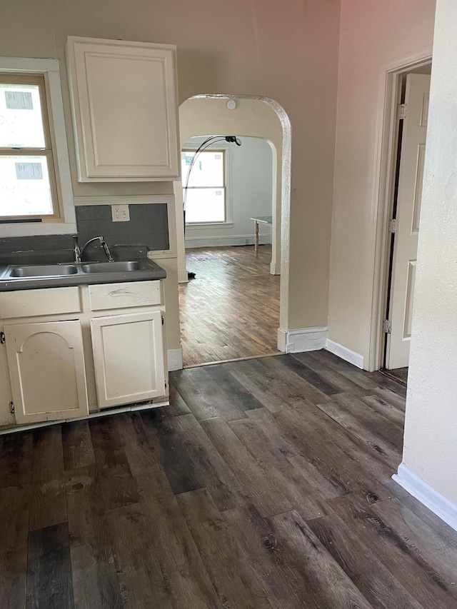 1122 Prospect St, Lansing, MI 48912 - kitchen featuring dark wood-style floors, baseboards, a sink, and white cabinets