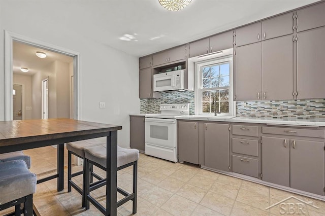 5200 Swede Ave, Midland, MI 48640 - kitchen with white appliances, gray cabinets, backsplash, light countertops, and a sink