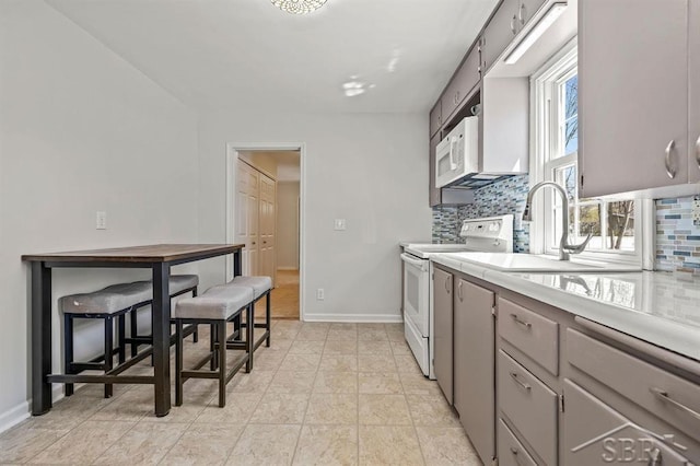 5200 Swede Ave, Midland, MI 48640 - kitchen featuring white appliances, tasteful backsplash, light countertops, a sink, and baseboards