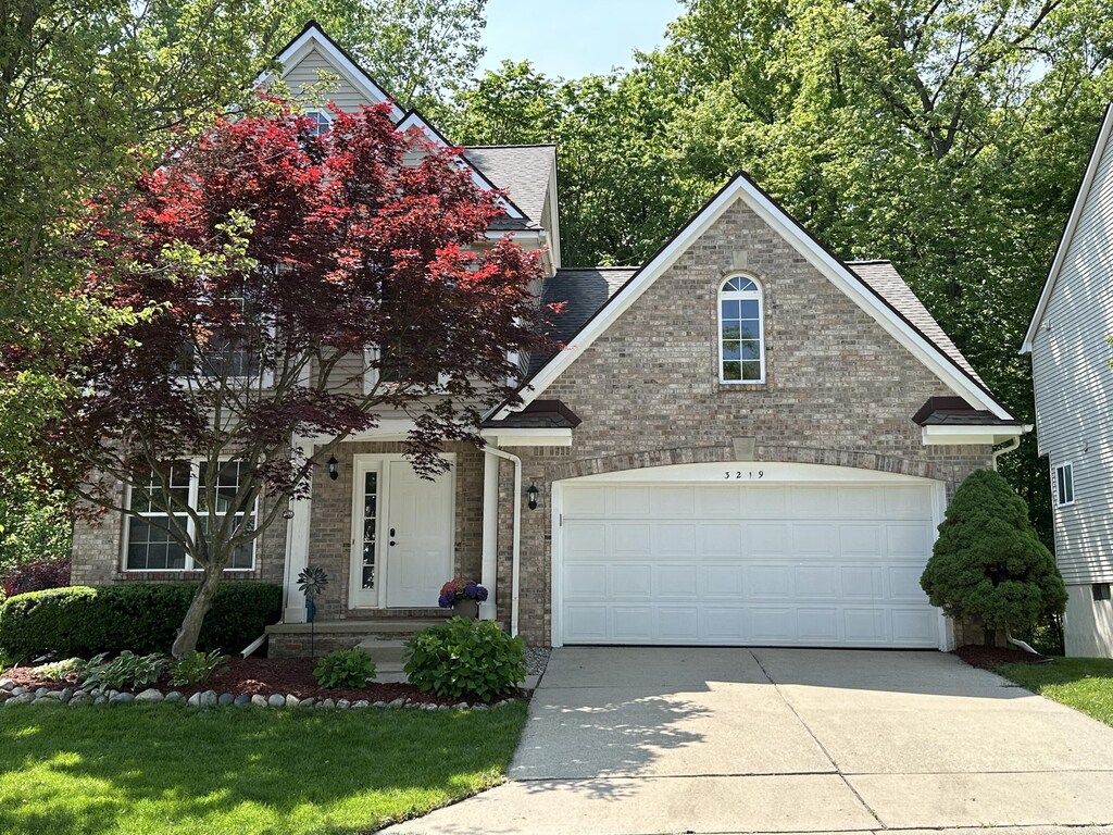 3219 Dunwoodie Rd, Ann Arbor, MI 48105 - view of front of property featuring brick siding, concrete driveway, a shingled roof, and an attached garage
