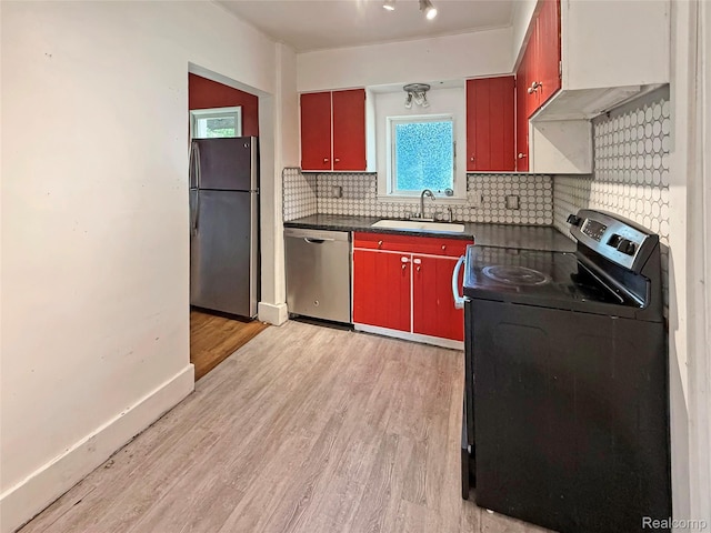 1408 Lincoln Dr, Flint, MI 48503 - kitchen featuring stainless steel appliances, a sink, red cabinetry, dark countertops, and light wood finished floors