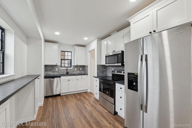 17772 Clark St, Riverview, MI 48193 - kitchen featuring stainless steel appliances, dark countertops, wood finished floors, backsplash, and white cabinets