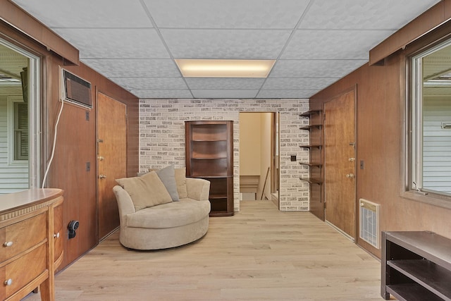 817 Cherry Ave, Big Rapids, MI 49307 - sitting room featuring a paneled ceiling, a wall mounted air conditioner, brick wall, light wood finished floors, and heating unit