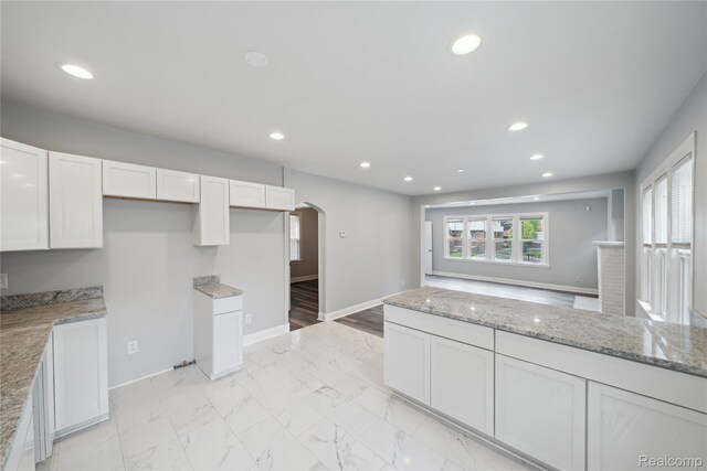 4835 Bedford St, Detroit, MI 48224 - kitchen with arched walkways, white cabinets, light stone countertops, recessed lighting, and baseboards