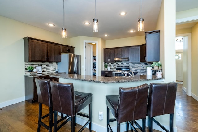 1640 Prairie Dr, Saint Joseph, MI 49085 - kitchen featuring stainless steel appliances, dark brown cabinets, tasteful backsplash, dark stone countertops, and dark wood-style flooring
