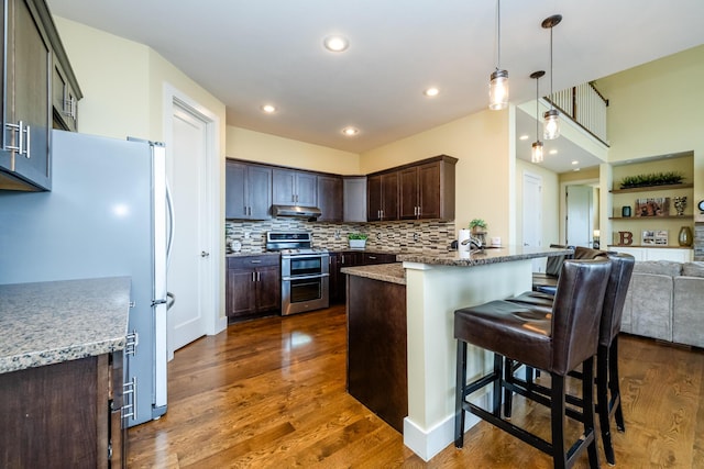 1640 Prairie Dr, Saint Joseph, MI 49085 - kitchen with range with two ovens, freestanding refrigerator, open floor plan, dark brown cabinetry, and a breakfast bar