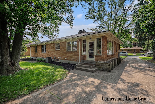 2308 Godwin Ave SE, Grand Rapids, MI 49507 - view of front of house with brick siding, a chimney, central air condition unit, a front yard, and driveway