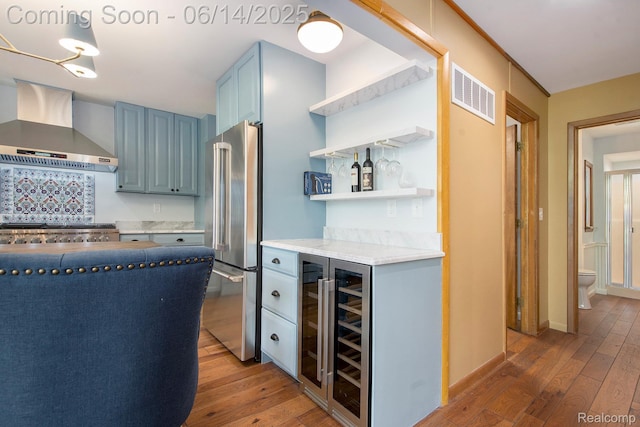 9818 Burning Tree Dr, Grand Blanc, MI 48439 - kitchen featuring wall chimney range hood, freestanding refrigerator, blue cabinets, light wood-style flooring, and open shelves