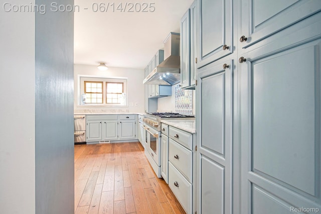 9818 Burning Tree Dr, Grand Blanc, MI 48439 - kitchen with range with two ovens, wall chimney range hood, light countertops, light wood-type flooring, and dishwasher
