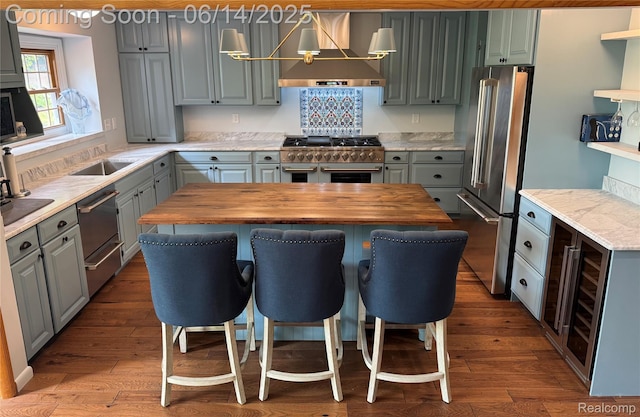 9818 Burning Tree Dr, Grand Blanc, MI 48439 - kitchen featuring high quality appliances, wall chimney exhaust hood, gray cabinetry, butcher block counters, and wine cooler