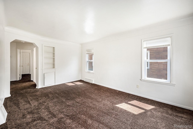 18930 Curtis St, Highland Park, MI 48219 - spare room featuring dark colored carpet, built in features, arched walkways, and baseboards