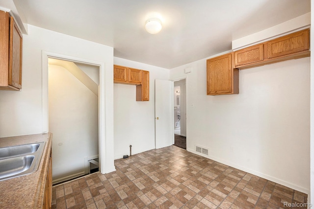 18930 Curtis St, Highland Park, MI 48219 - kitchen with brick patterned flooring, a sink, baseboards, and brown cabinetry