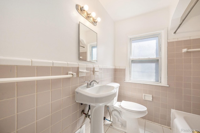 18930 Curtis St, Highland Park, MI 48219 - bathroom featuring tile walls, a bathtub, tile patterned flooring, toilet, and a wainscoted wall
