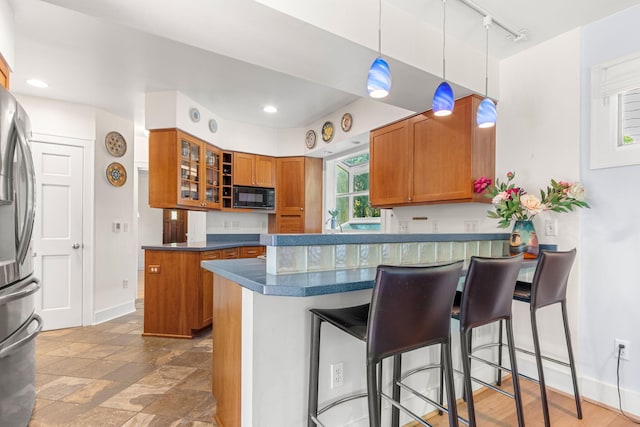1308 Linwood Ave, Ann Arbor, MI 48103 - kitchen with black microwave, brown cabinets, freestanding refrigerator, a peninsula, and track lighting