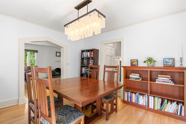 1308 Linwood Ave, Ann Arbor, MI 48103 - dining room with a chandelier, light wood-style flooring, crown molding, arched walkways, and baseboards