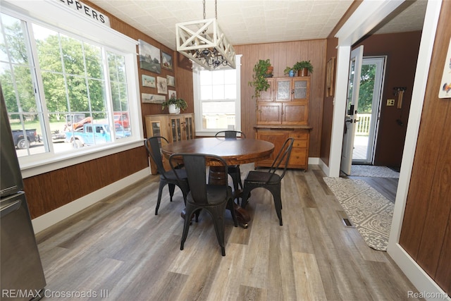 20375 Sumpter Rd, Belleville, MI 48111 - dining area featuring a chandelier, light wood finished floors, and wood walls