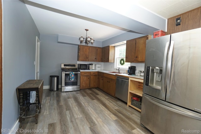 20375 Sumpter Rd, Belleville, MI 48111 - kitchen with appliances with stainless steel finishes, a chandelier, light countertops, wood finished floors, and brown cabinets