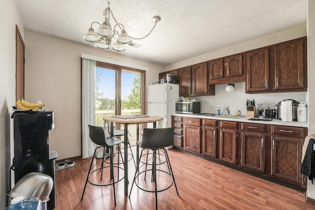 41 E 48th St, Holland, MI 49423 - kitchen featuring stainless steel microwave, freestanding refrigerator, a chandelier, light countertops, and a sink