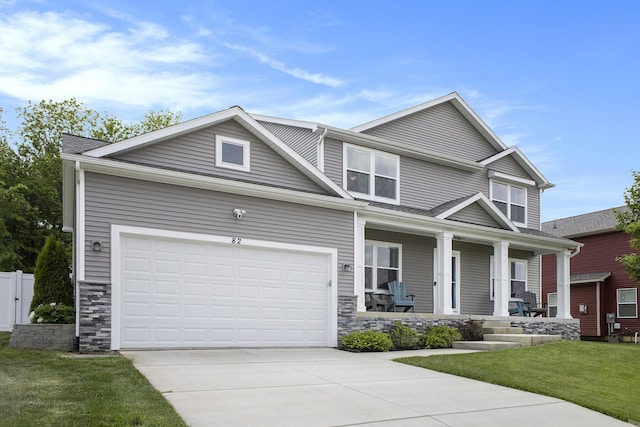 82 Dickens St, Spring Arbor, MI 49283 - view of front of house with a porch, concrete driveway, stone siding, and a front yard
