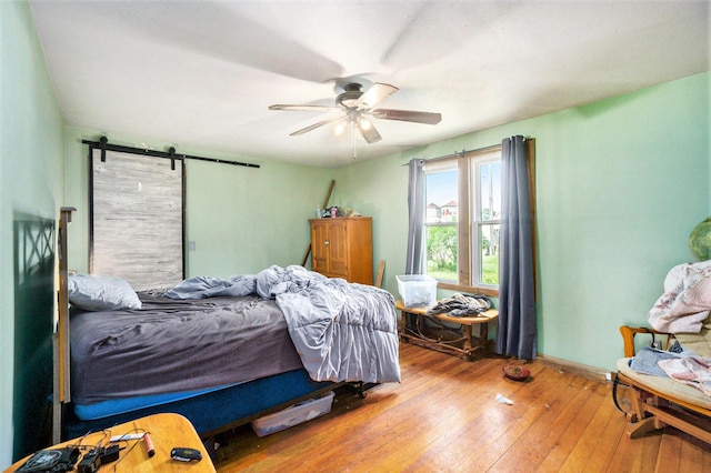 1027 E Railroad St, Hastings, MI 49058 - bedroom featuring wood-type flooring, a barn door, a ceiling fan, and baseboards