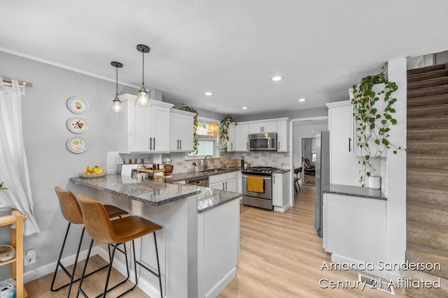 620 Emerald Ave NE, Grand Rapids, MI 49503 - kitchen with appliances with stainless steel finishes, a peninsula, white cabinets, dark stone counters, and decorative backsplash