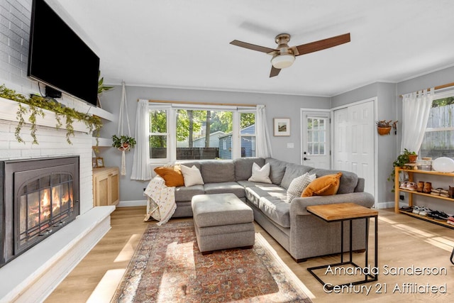 620 Emerald Ave NE, Grand Rapids, MI 49503 - living room with plenty of natural light, a ceiling fan, a brick fireplace, light wood-type flooring, and ornamental molding