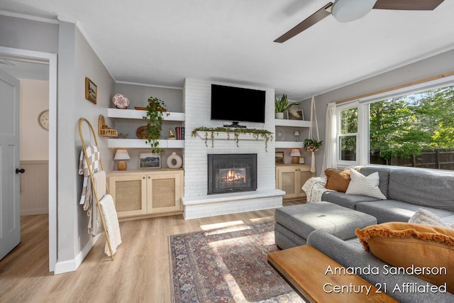 620 Emerald Ave NE, Grand Rapids, MI 49503 - living room with light wood-style flooring, ceiling fan, a brick fireplace, a wainscoted wall, and ornamental molding