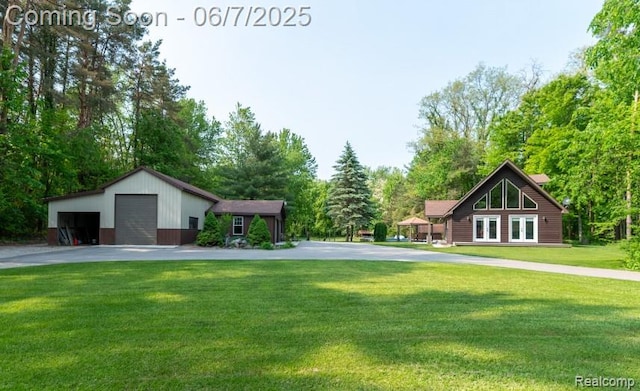 3591 Curry Rd, Caro, MI 48723 - view of grassy yard featuring a detached garage, view of wooded area, and french doors