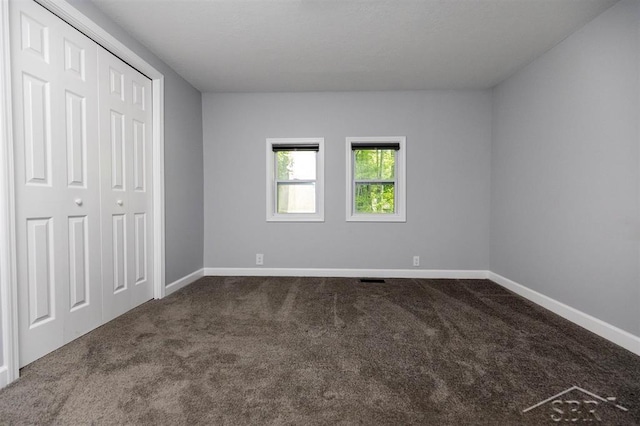 2832 N W River Rd, Sanford, MI 48657 - unfurnished bedroom with dark carpet, baseboards, and a closet