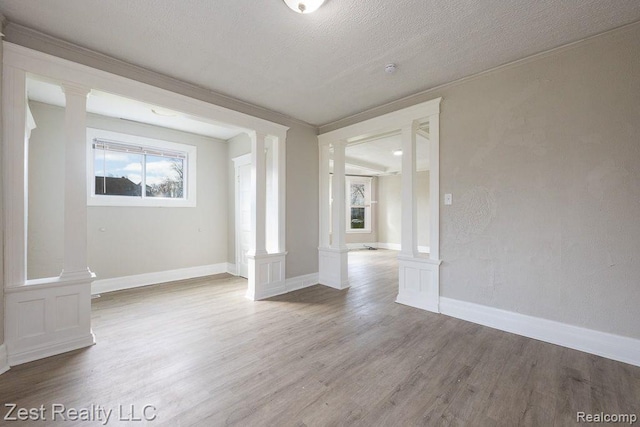 2977 Canton St, Detroit, MI 48207 - unfurnished room featuring decorative columns, wood finished floors, ornamental molding, baseboards, and a textured ceiling