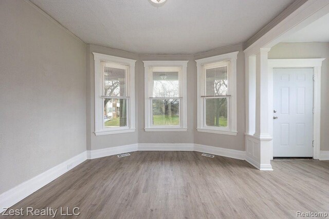 2977 Canton St, Detroit, MI 48207 - spare room featuring ornate columns, wood finished floors, baseboards, and ornamental molding