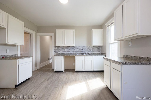 2977 Canton St, Detroit, MI 48207 - kitchen featuring light wood finished floors, white cabinetry, a sink, and backsplash