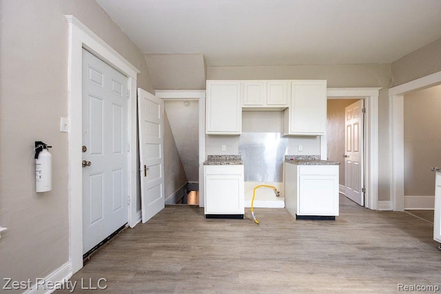 2977 Canton St, Detroit, MI 48207 - kitchen featuring white cabinets, light wood-style flooring, baseboards, and light stone countertops