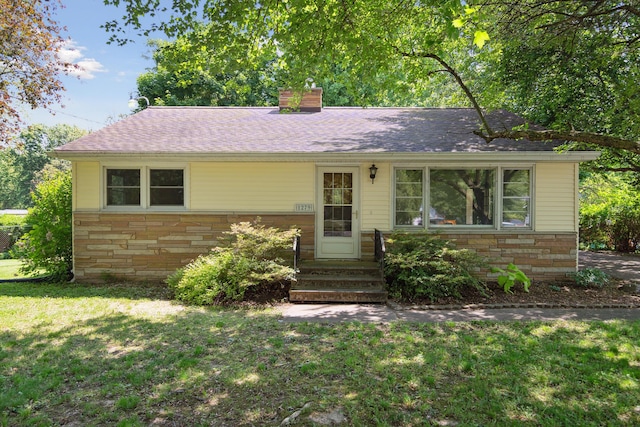 1279 Cunningham, Jackson, MI 49201 - ranch-style house with stone siding, a front yard, and a chimney