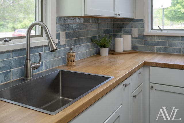 7936 Whitehall Rd, Whitehall, MI 49461 - kitchen view of a sink, butcher block counters, decorative backsplash, and white cabinetry