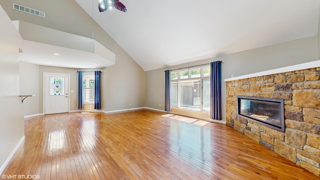 224 S Jameson St, New Buffalo, MI 49117 - unfurnished living room with a stone fireplace, light wood-style flooring, baseboards, and high vaulted ceiling