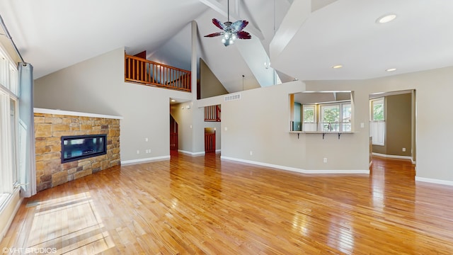 224 S Jameson St, New Buffalo, MI 49117 - unfurnished living room with ceiling fan, light wood finished floors, high vaulted ceiling, a stone fireplace, and baseboards