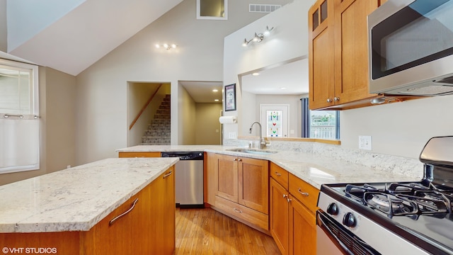 224 S Jameson St, New Buffalo, MI 49117 - kitchen with appliances with stainless steel finishes, a sink, light wood-style flooring, brown cabinetry, and light stone counters