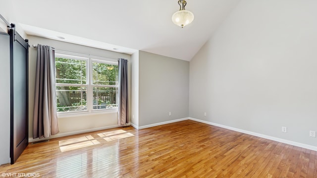 224 S Jameson St, New Buffalo, MI 49117 - spare room featuring light wood-type flooring, vaulted ceiling, a barn door, and baseboards
