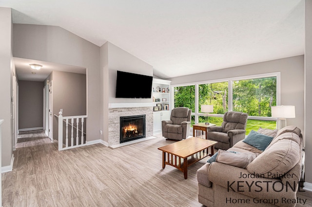 5896 Rollaway Dr NE, Comstock Park, MI 49321 - living room with vaulted ceiling, light wood-style flooring, baseboards, and a stone fireplace