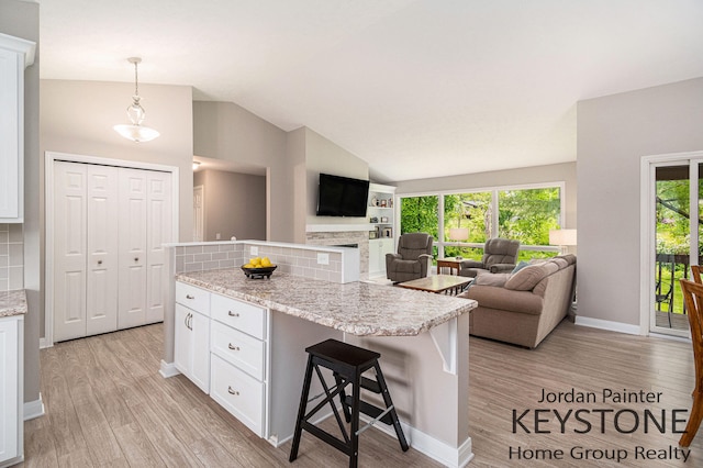 5896 Rollaway Dr NE, Comstock Park, MI 49321 - kitchen featuring lofted ceiling, tasteful backsplash, white cabinetry, light wood-style floors, and open floor plan