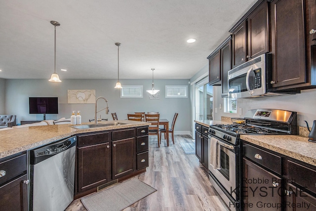 881 Cobblestone Way Dr SE, Byron Center, MI 49315 - kitchen featuring stainless steel appliances, a sink, dark brown cabinetry, light wood-style flooring, and light countertops