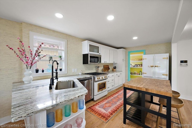 600 Wolverine Dr, Walled Lake, MI 48390 - kitchen featuring appliances with stainless steel finishes, a sink, white cabinetry, light wood-style floors, and glass insert cabinets