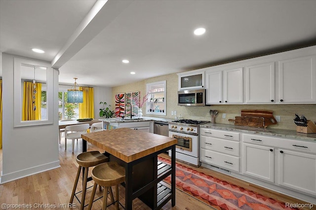 600 Wolverine Dr, Walled Lake, MI 48390 - kitchen featuring appliances with stainless steel finishes, white cabinetry, recessed lighting, tasteful backsplash, and light wood finished floors